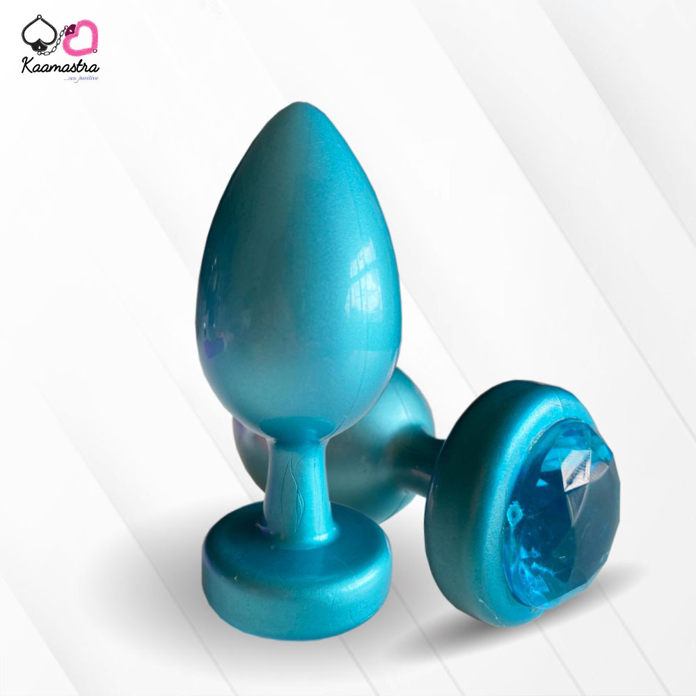 A collection of anal butt plugs in various colors, each featuring a crystal jewel at the base. The plugs are designed in a smooth, egg-shaped form.